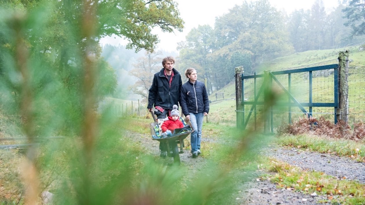 Familj gående på skogsväg.