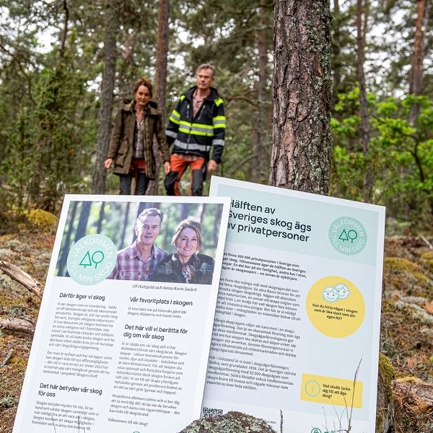 Presentationsskyltar för slingan "Välkommen till min skog" och en man och en kvinna i bakgrunden.